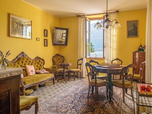 Una habitación con pared amarilla, un ventanal grande, un tablero de ajedrez y una mesa de comedor.