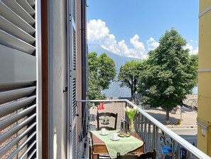 Ein Balkon mit einem Tisch für zwei Personen, mit Blick auf einen See, Bäume und einen Berg im Hintergrund.