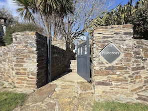 Eine Steinmauer mit einem Tor und einem Schild, auf dem 'Pinecroft' steht.