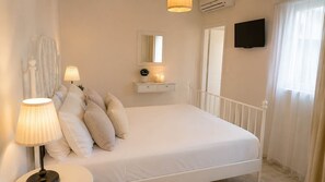 Ein Schlafzimmer mit einem Bett, Nachttischlampen, einem Spiegel, einem Fernseher und einem Fenster mit Vorhängen.