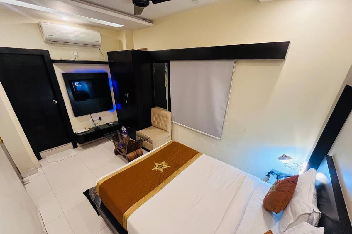 Una habitación de hotel con cama, televisor, sofá y ventana.
