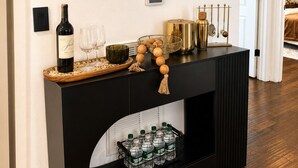A black console table with a wine bottle, glasses, a fruit bowl, and a water dispenser. - Welcome to The Woven Nest Near NYC  (Paterson)