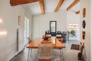 A modern dining area with a wooden table, chairs, and a large mirror. - A slice of paradise (Rustrel)