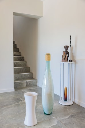 Eine Treppe, eine hohe Vase und eine kleine Statue auf einem weißen Sockel.