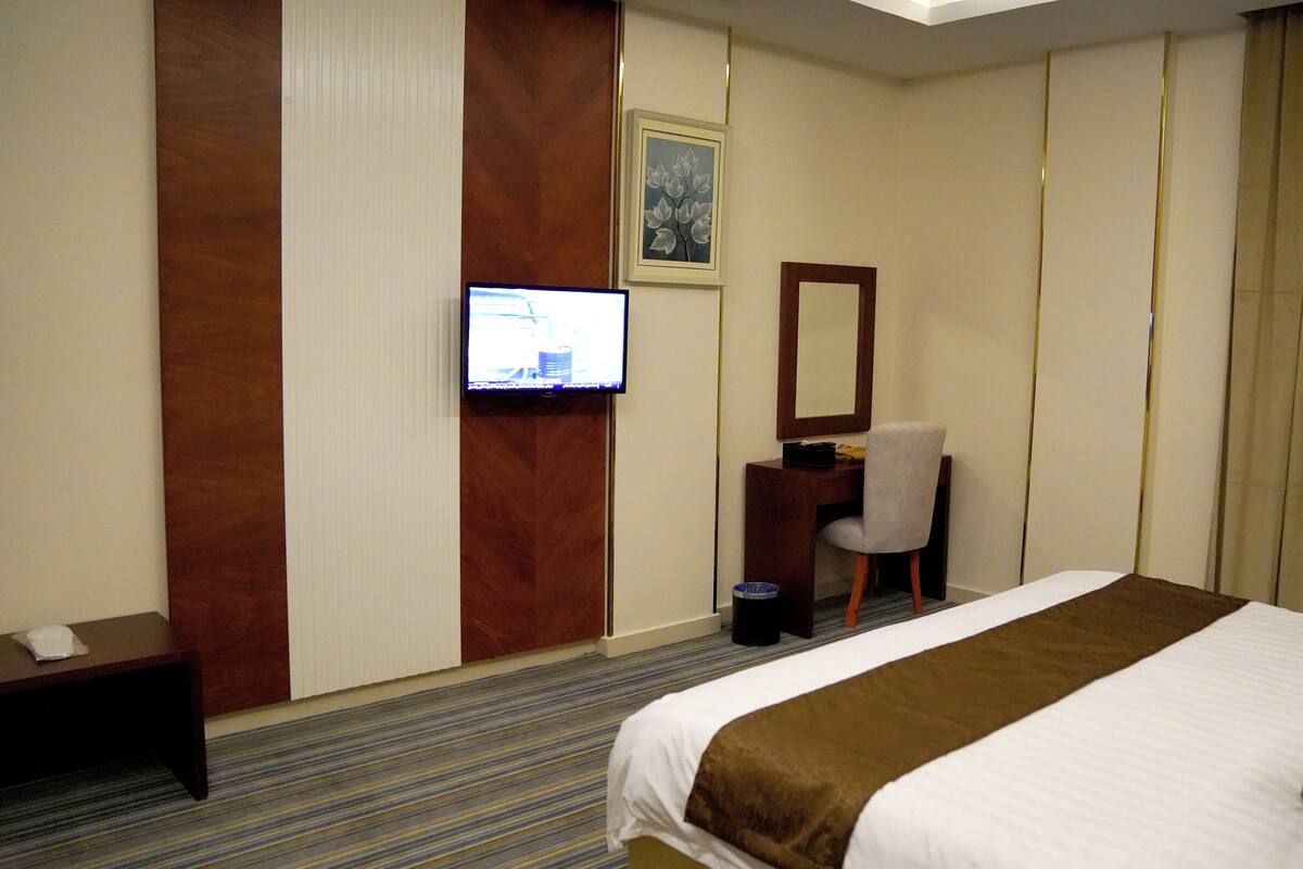 A hotel room with a bed, a desk, a chair, a television, and a picture on the wall.