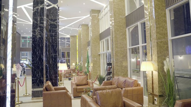 Un vestíbulo con columnas de mármol, sofás de cuero y una mesa de recepción.