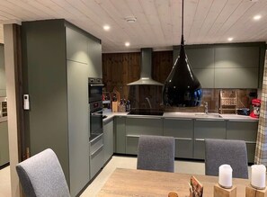 Ett modernt kök med grå skåp, en köksö och en matplats med bord och stolar.