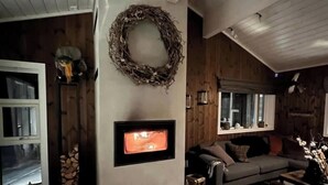 Een gezellige woonkamer met een open haard, een bank en een krans aan de muur.