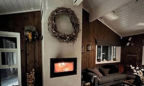 Ein gemütliches Wohnzimmer mit Kamin, einer Couch und einem Kranz an der Wand.