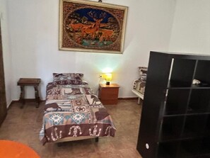 Ein Schlafzimmer mit einem Bett, einem Nachttisch, einer Lampe, einem gerahmten Bild an der Wand und einer Tür.