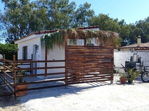 A small wooden structure with a thatched roof, a white wall, and a wooden fence. - Yellowstown Sunflower (Chiclana)