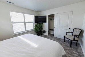 A bedroom with a bed, a TV, a potted plant, a chair, and a closet. - Welcome to Boise Grove — a thoughtfully designed, modern retreat in one of Boise’s most exciting and fast-growing neighborhoods. Located in Garden City, just steps from greenbelt, E bikes for rent (Garden City)
