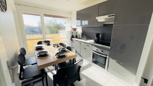Een moderne keuken met een eethoek, grote ramen en uitzicht op de omgeving.