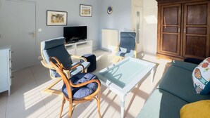 Een woonkamer met een televisie, een bank, een salontafel en een kast.