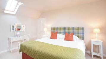A bedroom with a bed, a desk, a chair, two bedside tables, and a window.