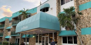A hotel with a distinctive turquoise awning and stone facade.