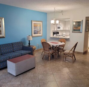 A living room with a blue wall, a sofa, a coffee table, and a dining area with chairs and a table.