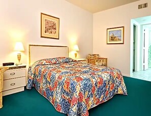 Une chambre à coucher comprenant un lit, deux tables de chevet, une commode et deux lampes fixées au mur.