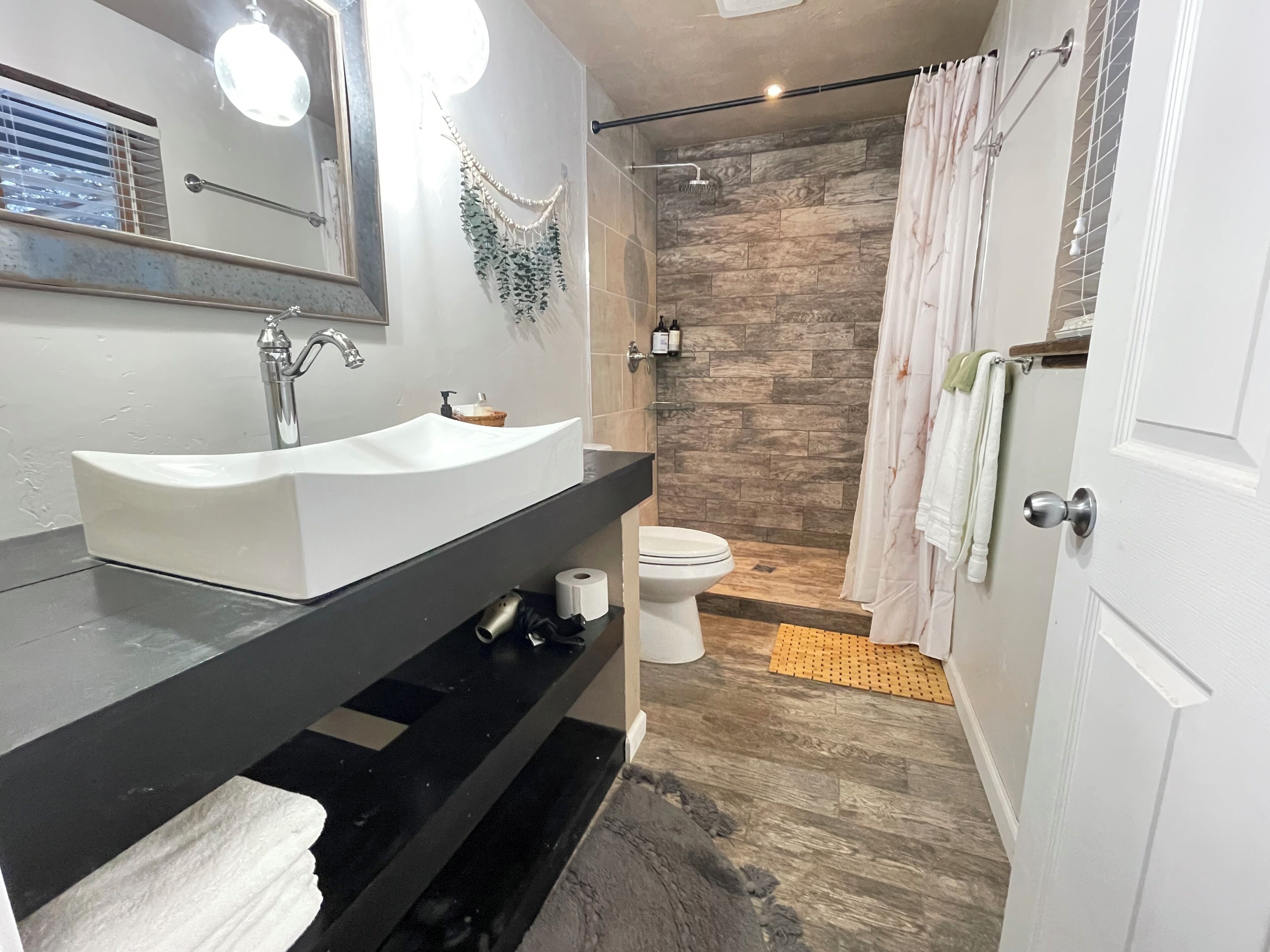 A bathroom with a sink, toilet, shower, and a towel rack.