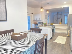 A modern kitchen with white cabinets, a central island, and a dining area with a patterned tablecloth. - Enjoyable 3-bedroom cabin with AC in charming Crandon walkingdistanceMetongaLake (Crandon)