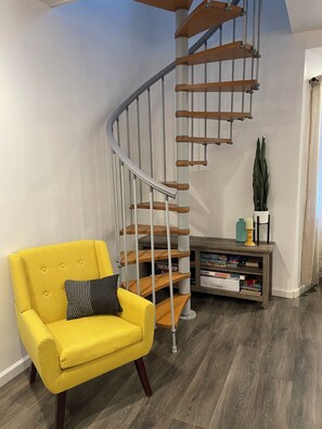 A modern interior with a spiral staircase, a yellow armchair, and a bookshelf. - Enjoyable 3-bedroom cabin with AC in charming Crandon walkingdistanceMetongaLake (Crandon)