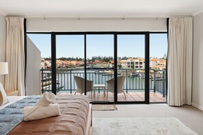 A hotel room with a bed, a small table, two chairs, a view of a body of water, and a balcony with a railing. - 3BR Marina View Retreat | Waterfront Living at Hartog Pass with own private access jetty (Wannanup)