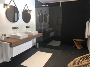 Un baño moderno con dos lavamanos, espejos y ducha.