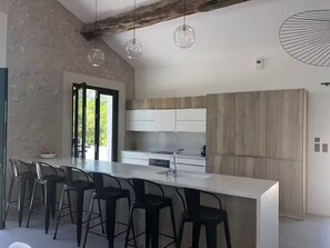Una cocina moderna con una isla grande, taburetes de bar e iluminación colgante.