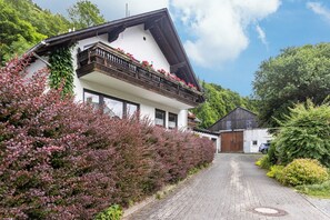 A traditional chalet with a sloped roof, wooden balcony, and a pathway leading to the entrance. - Apartment 'Fewo B' at the Golf Course with Mountain View, Balcony and Wi-Fi (Willingen)