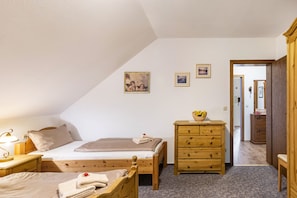 A bedroom with a bed, a wooden dresser, a nightstand, and a lamp. - Apartment 'Fewo B' at the Golf Course with Mountain View, Balcony and Wi-Fi (Willingen)