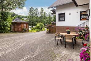 A cobblestone path leading to a house with a garden and outdoor seating area. - Apartment 'Fewo B' at the Golf Course with Mountain View, Balcony and Wi-Fi (Willingen)