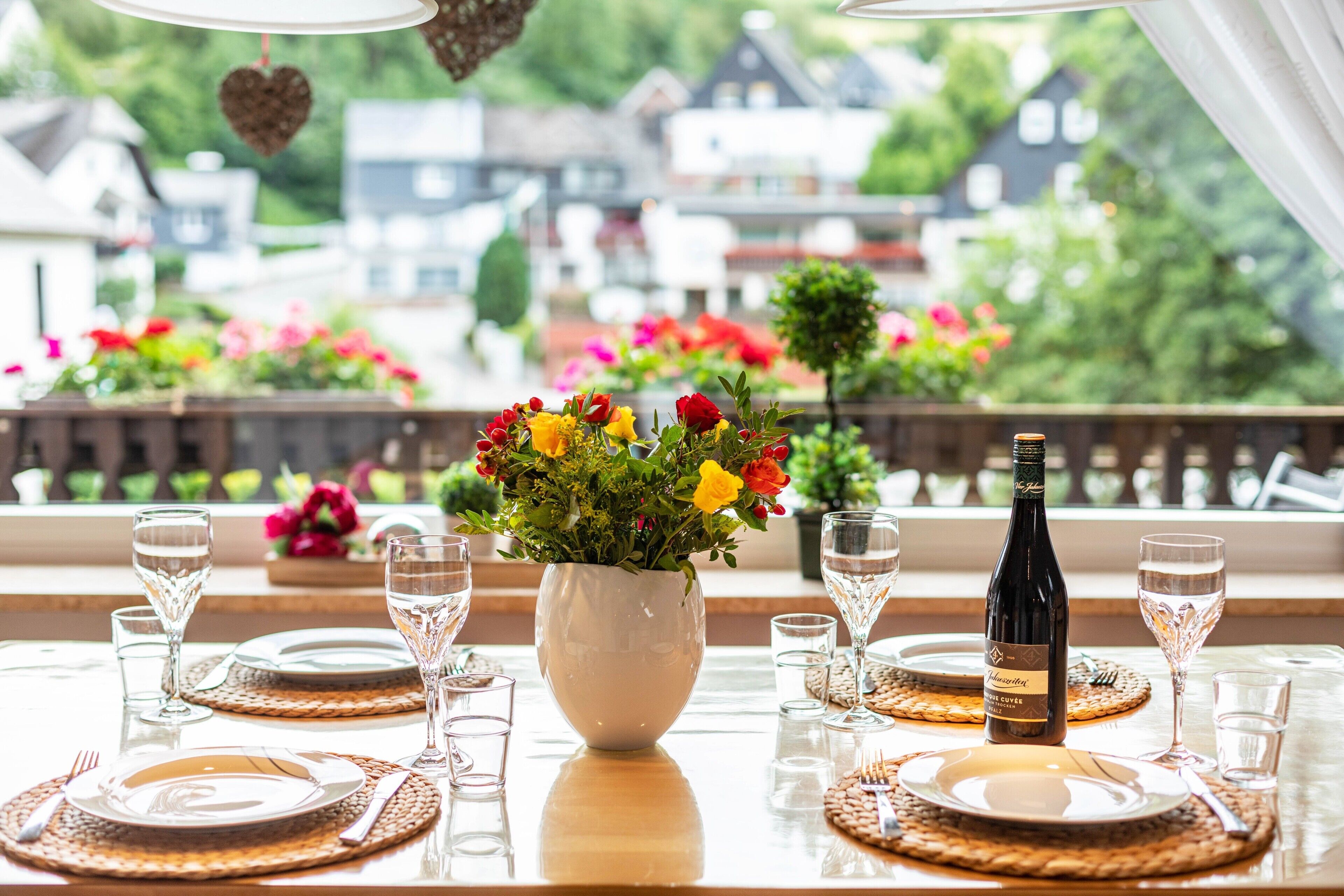 Une table mise pour le dîner, avec une bouteille de vin, des verres et un vase de fleurs.