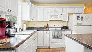 Una cocina con armarios blancos, un microondas, una estufa y un refrigerador.