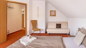 Une chambre à coucher comprenant un lit, un canapé, une chaise, un porte-manteau et un élément de décoration murale.