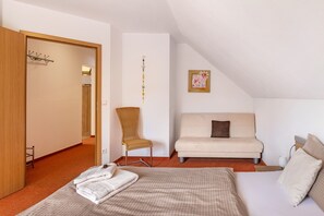 A bedroom with a bed, a sofa, a chair, a coat rack, and a wall decoration. - Apartment 'Ferienwohnung am Golfplatz' Fewo A with Mountain View, Balcony and Wi-Fi (Willingen)