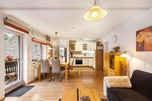 Eine moderne Küche mit Holzausstattung, ein Essbereich mit Tisch und Stühlen sowie ein Wohnzimmer mit Sofa und Lampe.