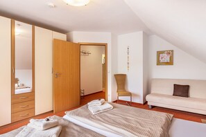 Een slaapkamer met een bed, een houten garderobe, een stoel, een bank en een schilderij aan de muur.