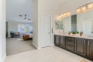 A modern bathroom with a large mirror, dark cabinets, and a light-colored floor.