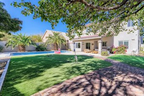 A residential property with a swimming pool, a patio with outdoor furniture, and a well-maintained lawn.