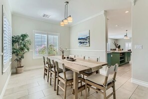 A dining area with a wooden table and chairs, a potted plant, and a painting on the wall.
