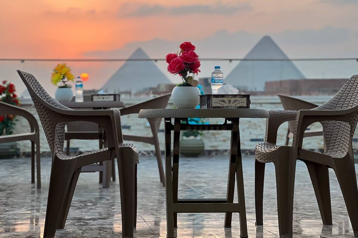A table with chairs, a vase with flowers, a water bottle, and a decorative item on the table.