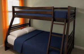 A bunk bed with a wooden frame, two pillows, and a blue bedspread.