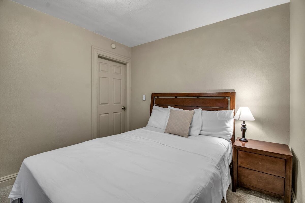 A bedroom with a bed, a nightstand, and a door.