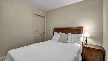 A bedroom with a bed, a nightstand, and a door.