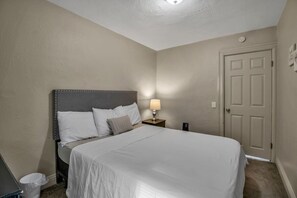 A bedroom with a bed, bedside lamp, and a door. - Niagara Falls Retreat (Niagara Falls)