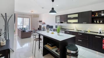 Une cuisine moderne avec des meubles de couleur sombre, un îlot central et un coin repas comprenant un canapé et des chaises.