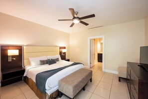 Ein Hotelzimmer mit Bett, Sitzbank, Fernseher und Deckenventilator.