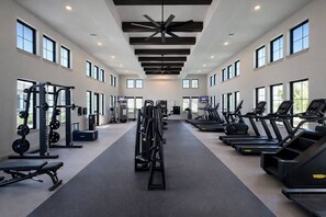 A gym with treadmills, weight machines, and a ceiling fan.
