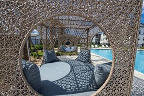 A circular outdoor seating area with a view of a pool and a building in the background.