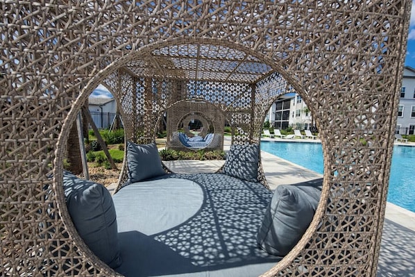 Un espace extérieur circulaire aménagé avec des sièges, offrant une vue sur une piscine et un bâtiment en arrière-plan.